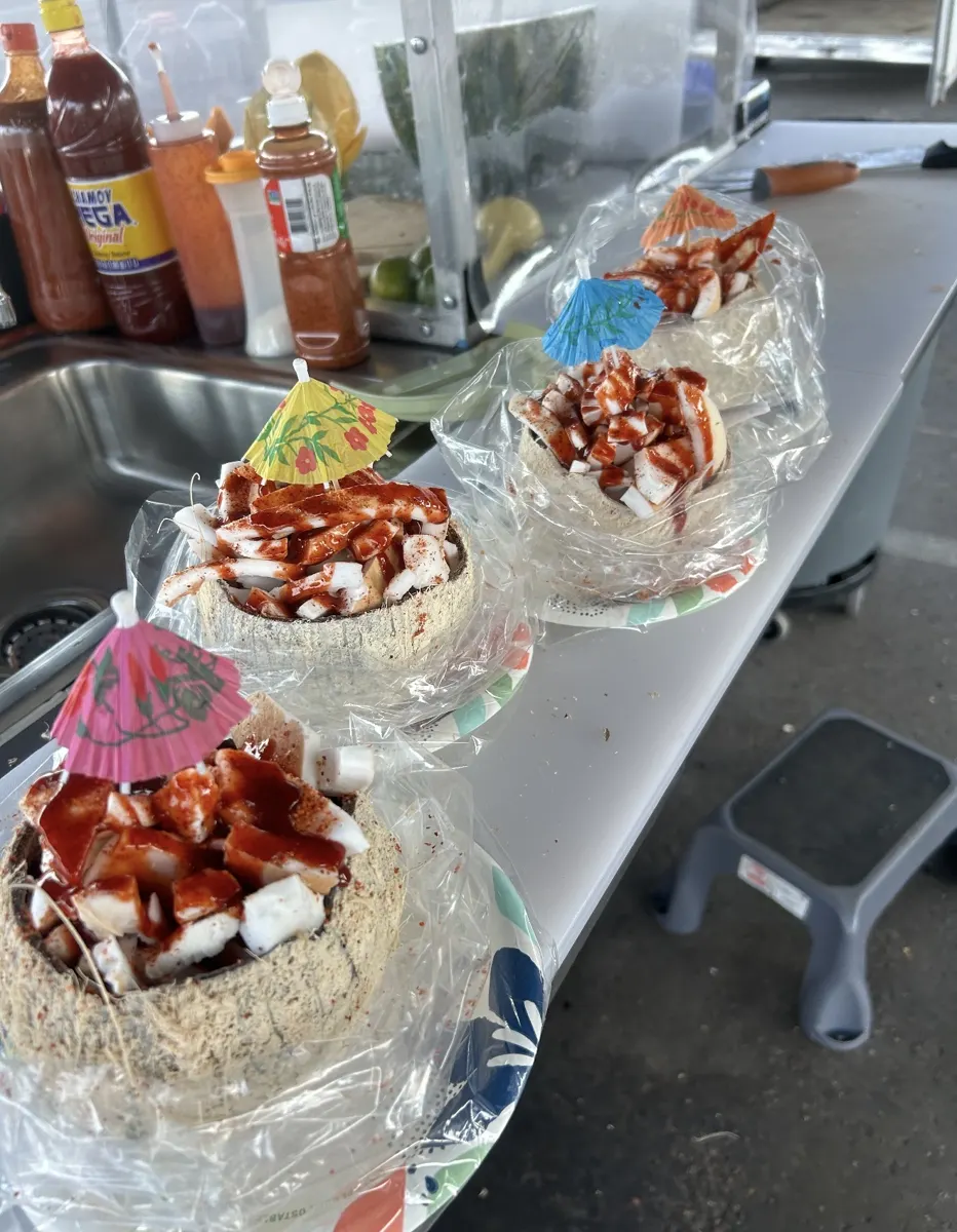Cocos rellenos de coco picado con chamoy y sombrillitas